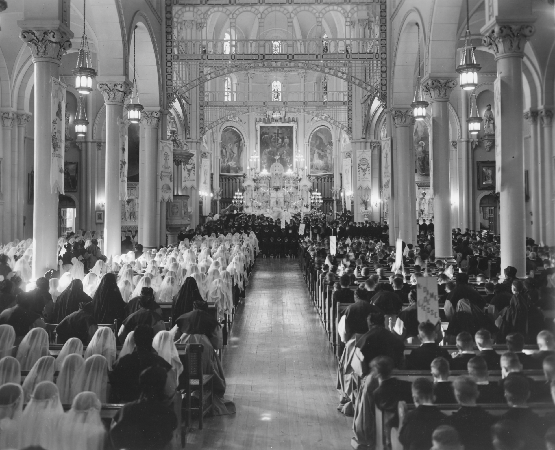 A historic photograph showing a large congregation attending a ceremony in a church with ornate interiors and stained glass.