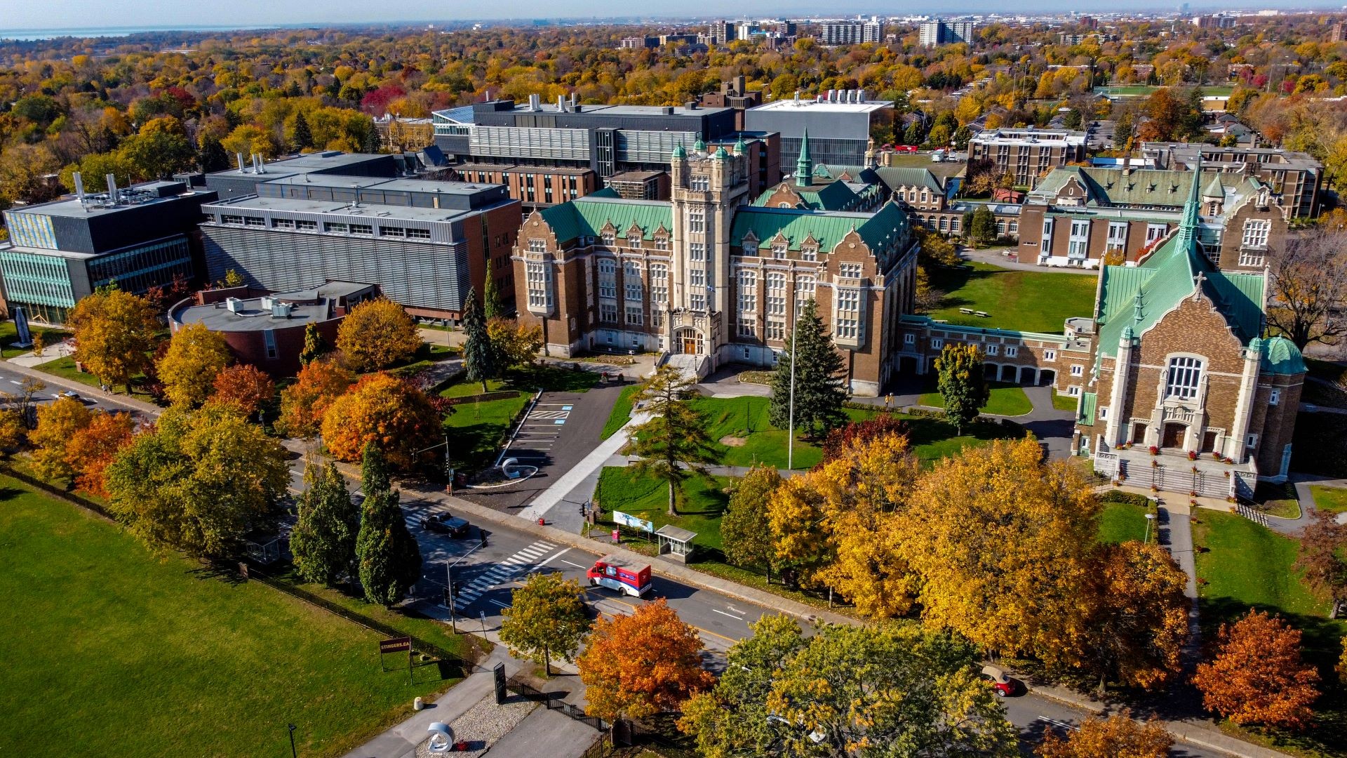 An aerial view of a university campus blending modern and historic buildings amidst autumn foliage.