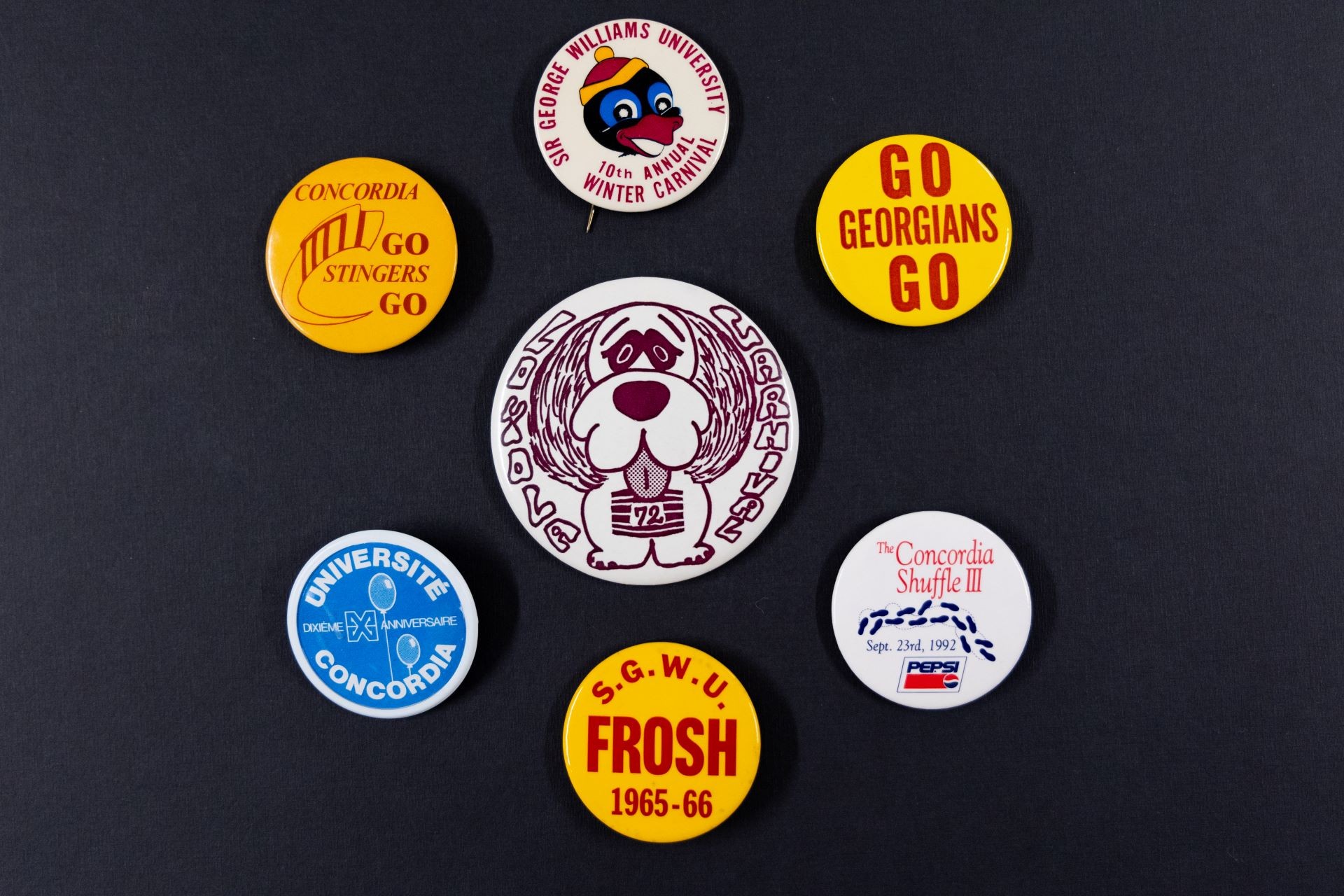 A collection of six assorted badges with different logos and text representing various university events and milestones.