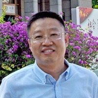 Portrait of a man smiling and wearing glasses and a button-up shirt