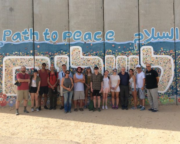 Participants stand in front of a painted mural in Israel