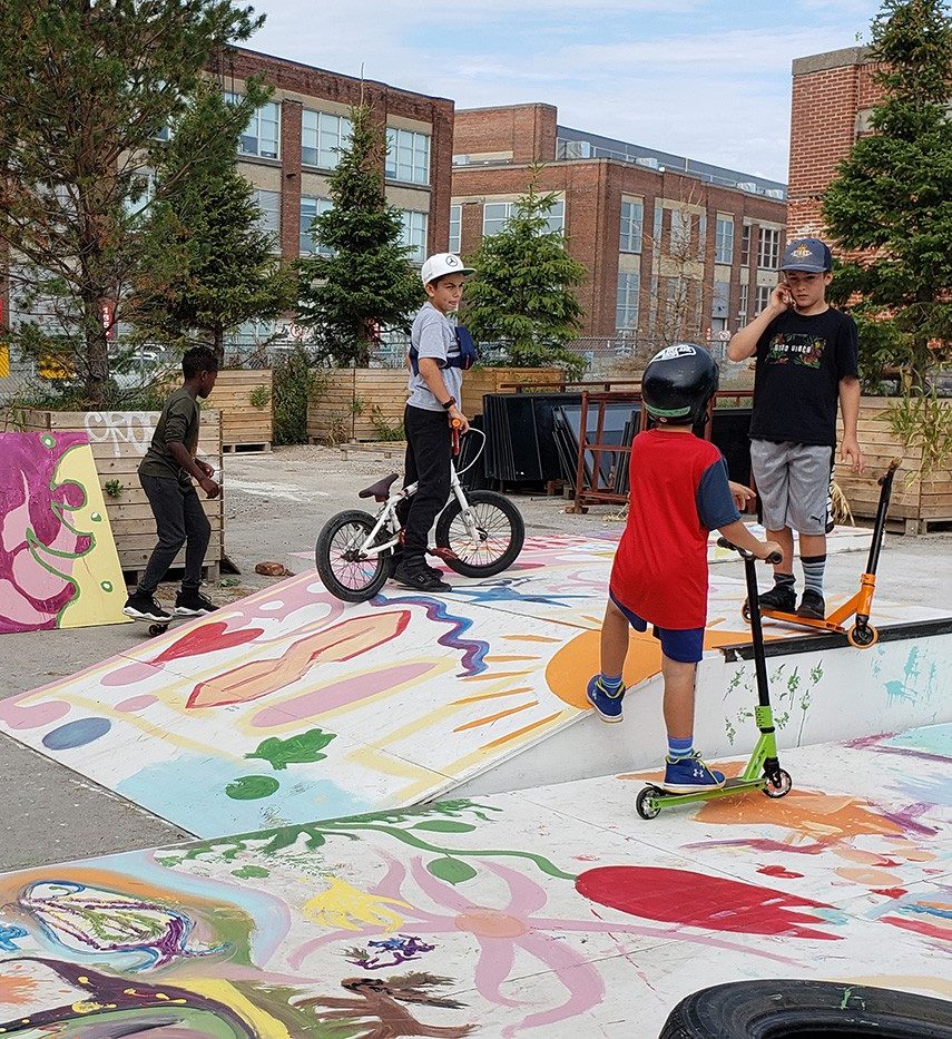 A colourful skatepark with kids playing.