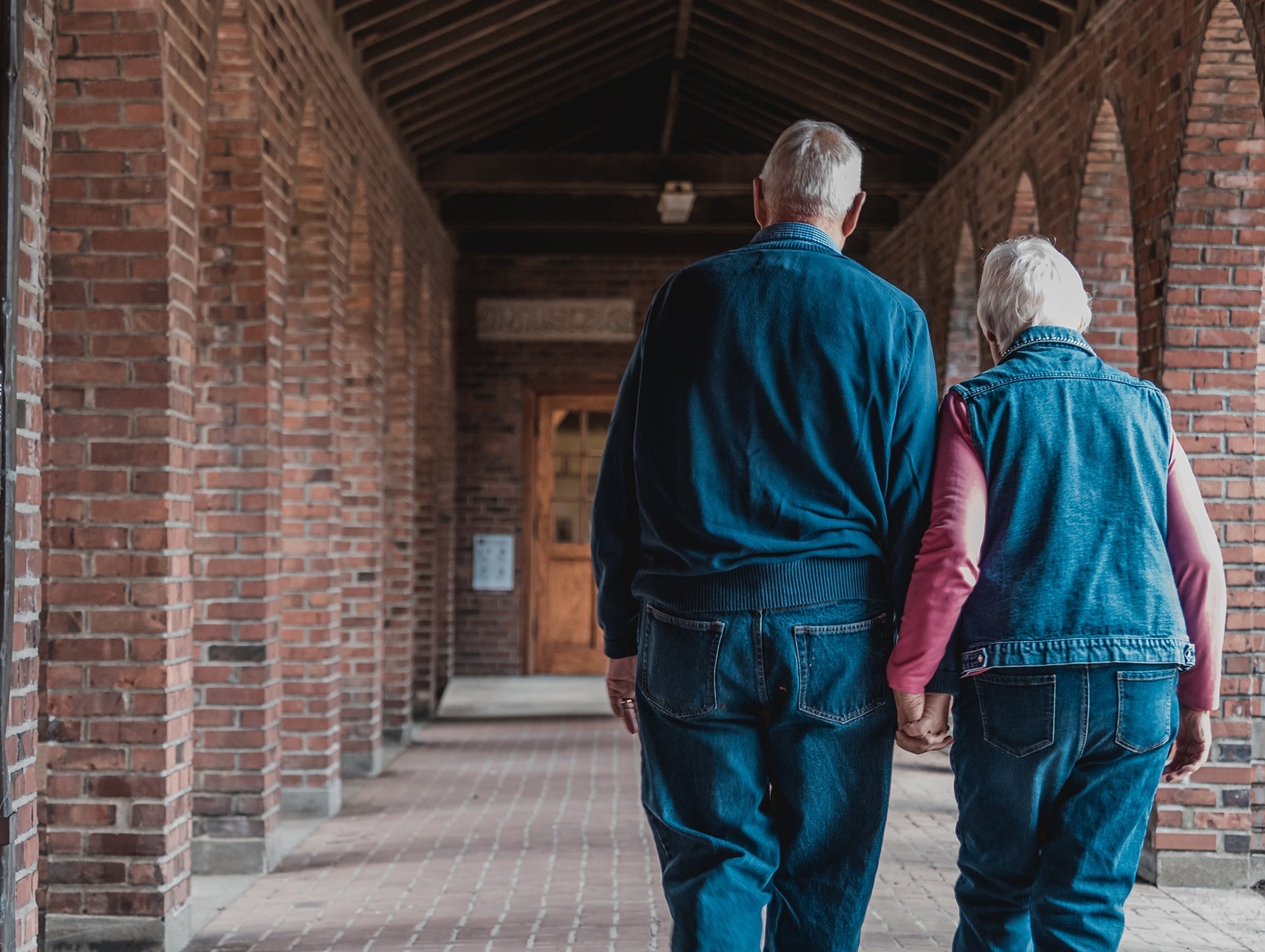 An elderly couple walk away hand-in-hand