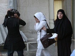 Morality Police officer apprehending two women in the streets of Tehran for wearing improper hijab.