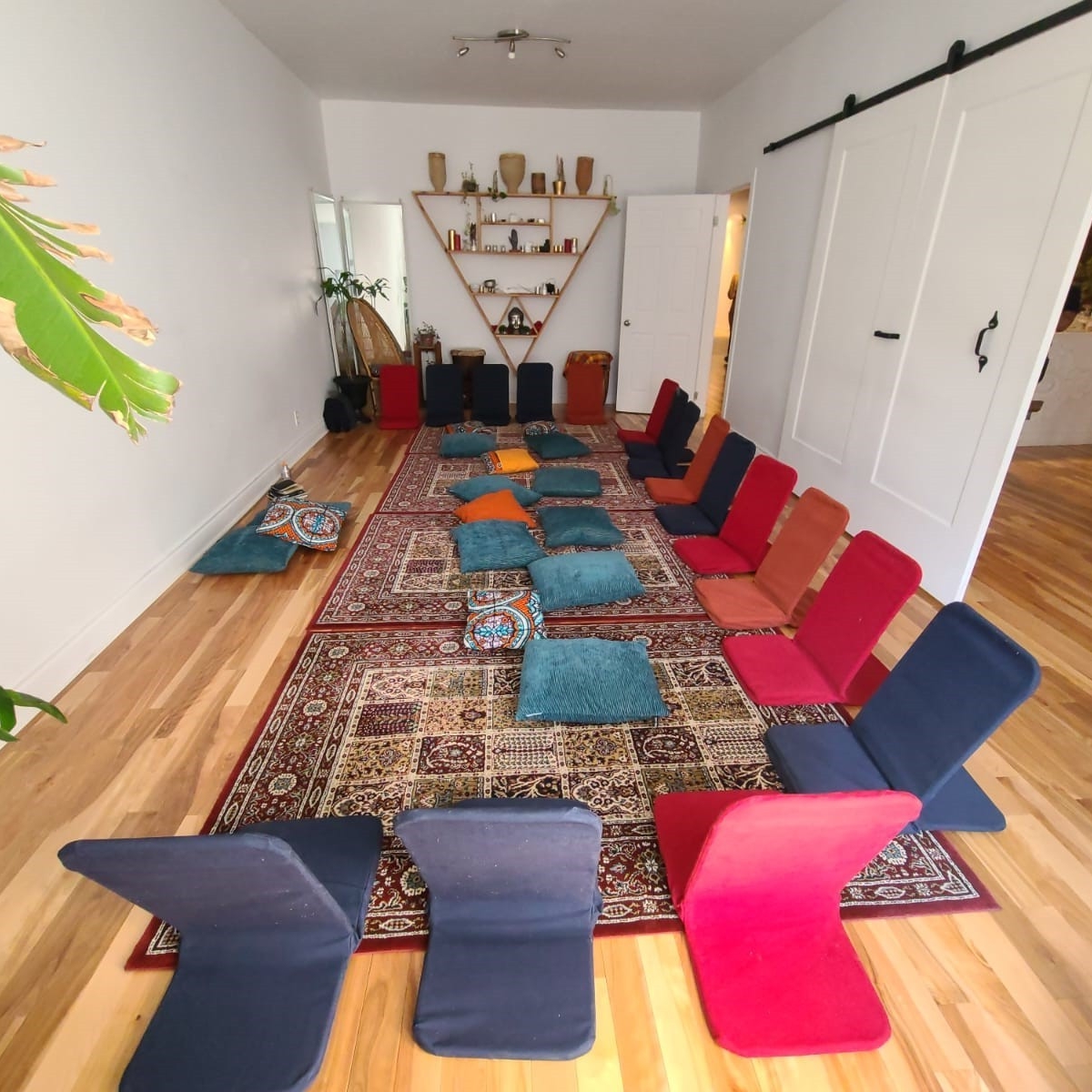 Une salle avec des coussins et chaises colorées prêt pour un atelier/cercle de guérison