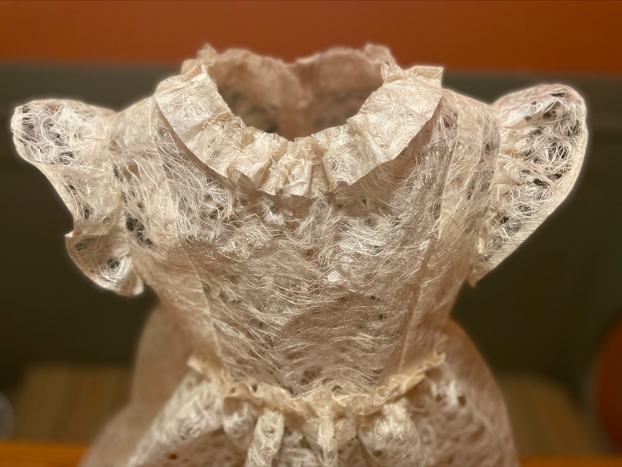 Child's dress showing waist, bodice, collar and sleeves; looks made of lace, but it is made of paper