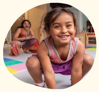 Young toddler squatting and smiling in a playroom