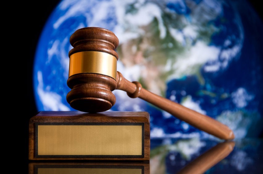 A gavel propped up on a stand with picture of earth in background