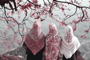 Photo of Muslim women sitting beneath a cherry blossom tree