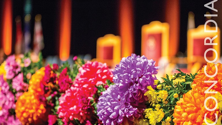 Bunches of colourful flowers in the foreground, with a stage in the background.