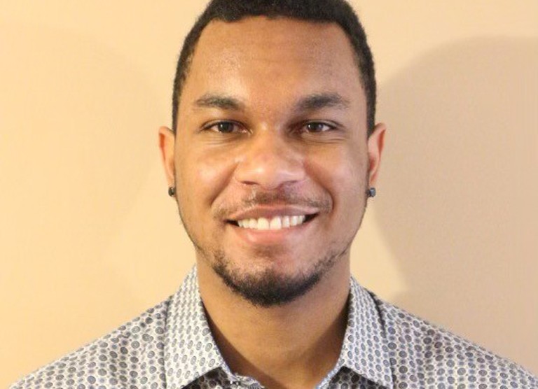 Young, smiling Black man with a patterned dress shirt.