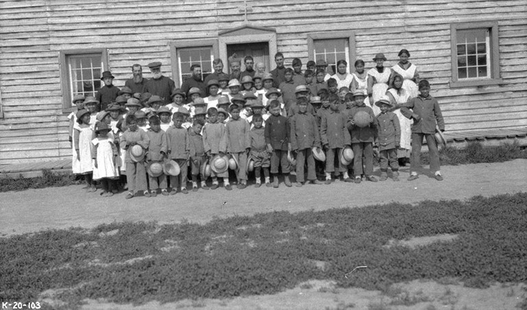 Archive photo of officials and schoolchildren outside Providence Mission Indian Residential School, Fort Providence, Northwest Territories