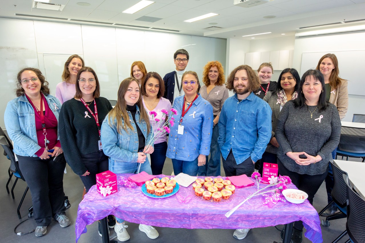 Student Success Centre employees wearing pink ribbons and denim jeans behind a bake sale table