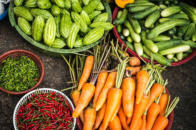 An array of fresh, raw vegetables, including carrots, cucumbers and chilis.