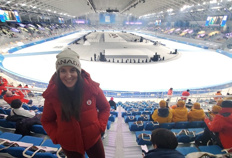 Smiling woman with a Team Canada tuque standing in a massive sports auditorium