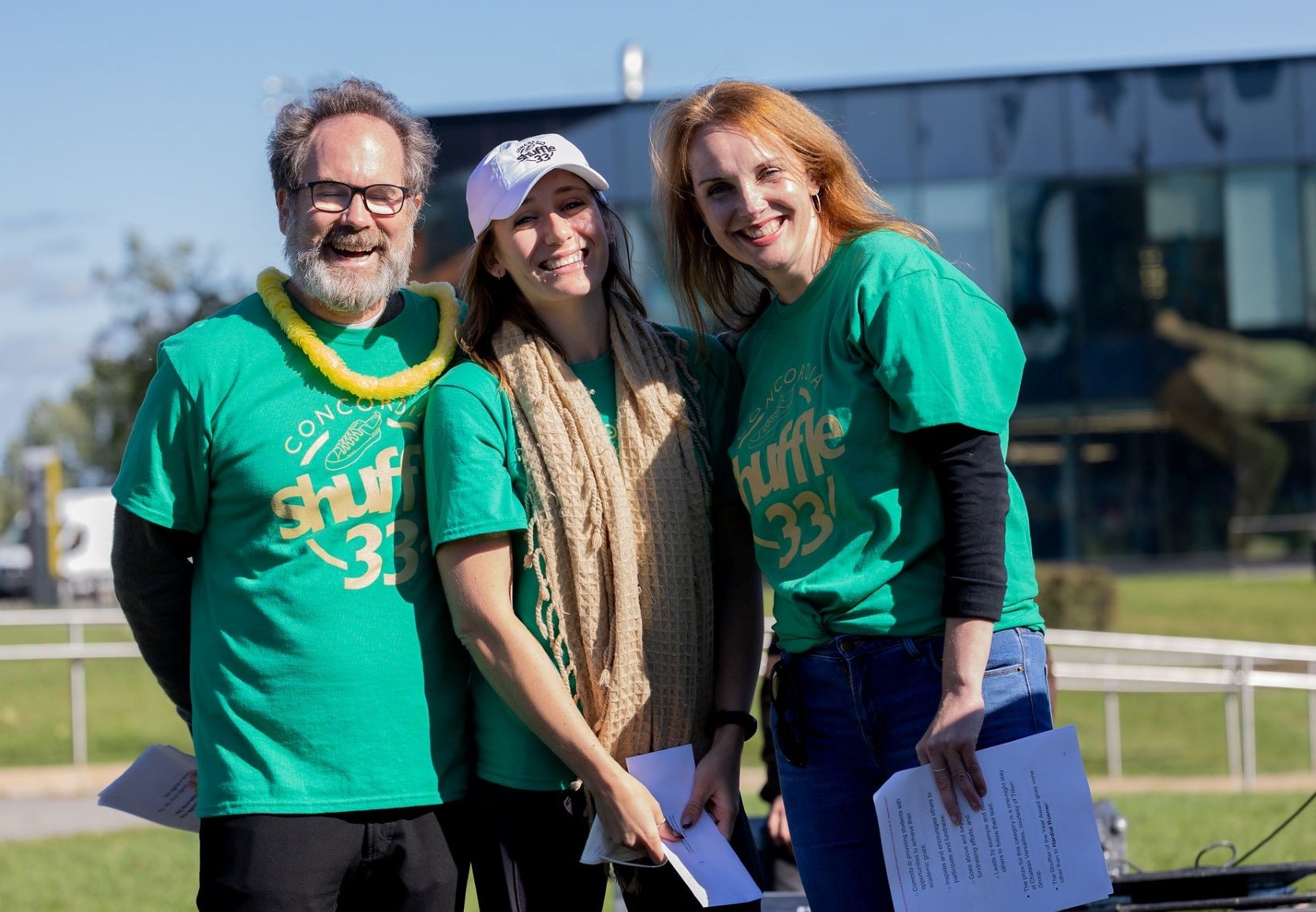 Three people standing together wearing green Shuffle T-shirts