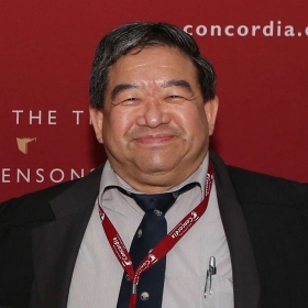 Paul Hwang smiles, wearing a suit in front of a Concordia banner