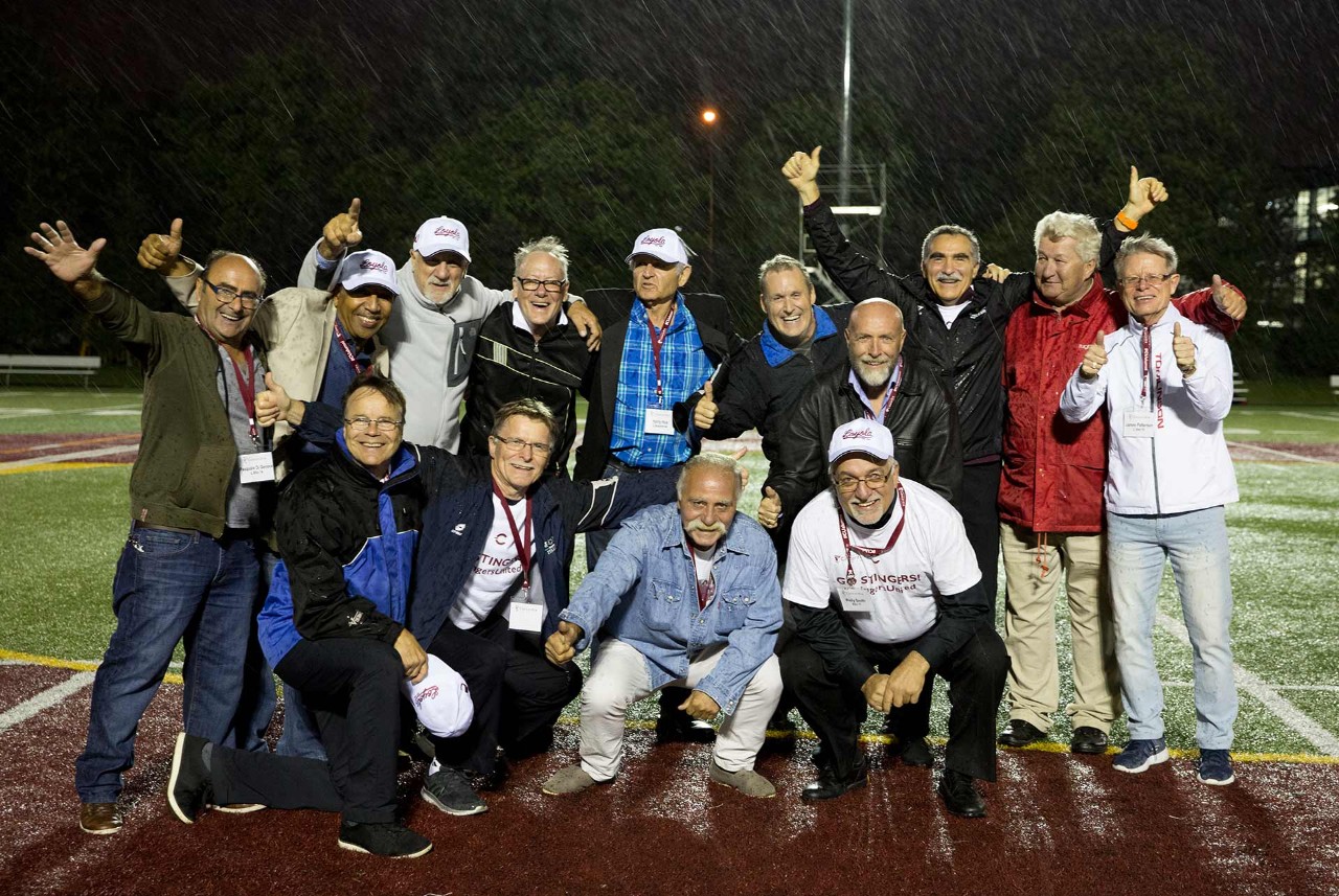 A group of men pose in the rain on a soccer field