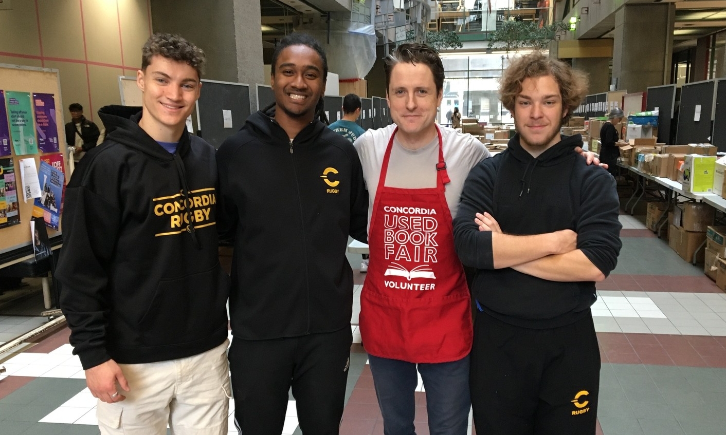 Four men stand in Concordia's Library Building atrium. They are all volunteers with Concordia's used book giveaway.