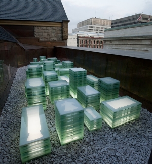 A series of glass rectangles sit in underlit pileson a gravel rooftop.