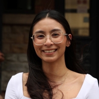 Portrait of a woman with long, dark hair, wearing glasses and a white top