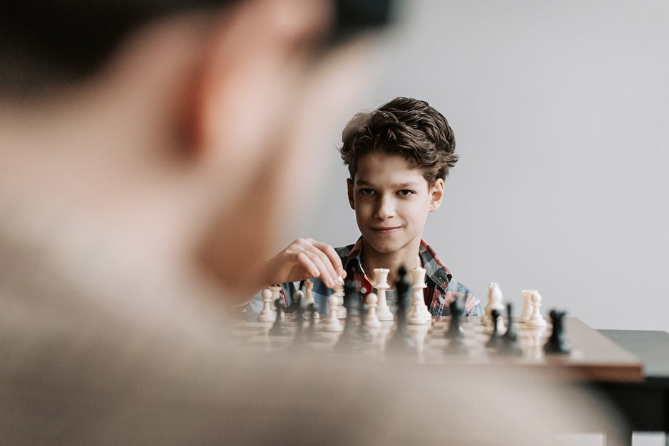 Kid playing chess with grin on his face