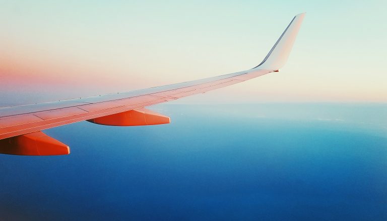 Pictured: the wing of an aeroplane in flight above the ocean at sunrise.