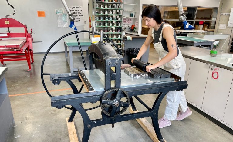 Young woman in an art studio using a lithographic press