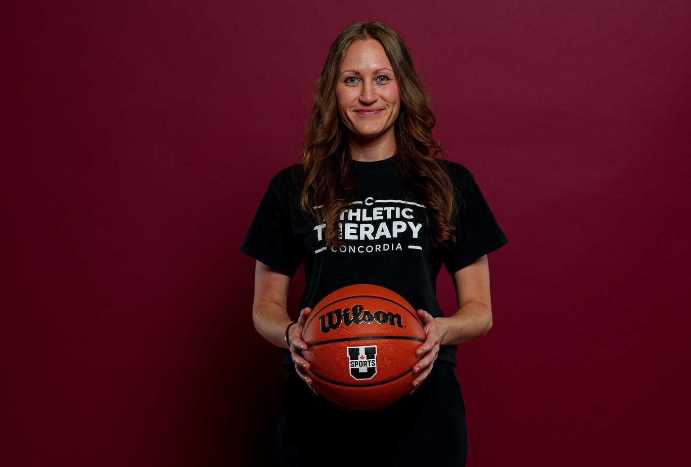 Meagan Anstruther wears a black t-shirt and holds a basketball