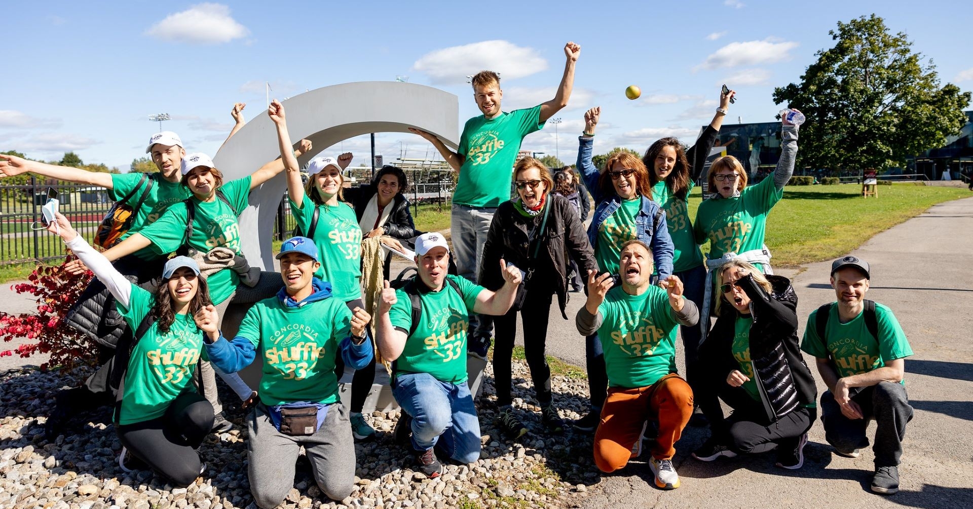 Un groupe de personnes excitées portant des T-shirts verts de la Marche de Concordia se rassemble sur le campus de Loyola.