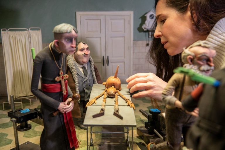 Une femme ajuste une figurine en stop-motion sur le tournage du film Pinocchio de Guillermo del Toro