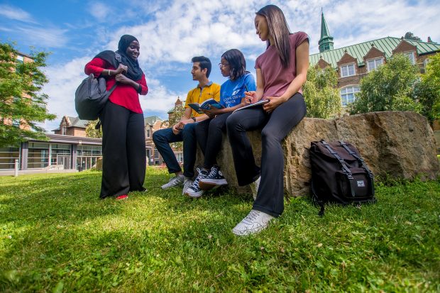 Four students engaged in a casual conversation on campus.