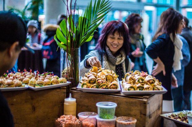 Woman sampling a wrap from a buffet table at the Taste of a Good Cause event