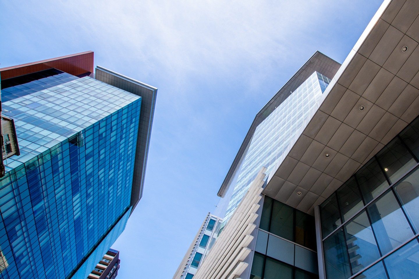Upward view of modern glass buildings with blue sky in the background.