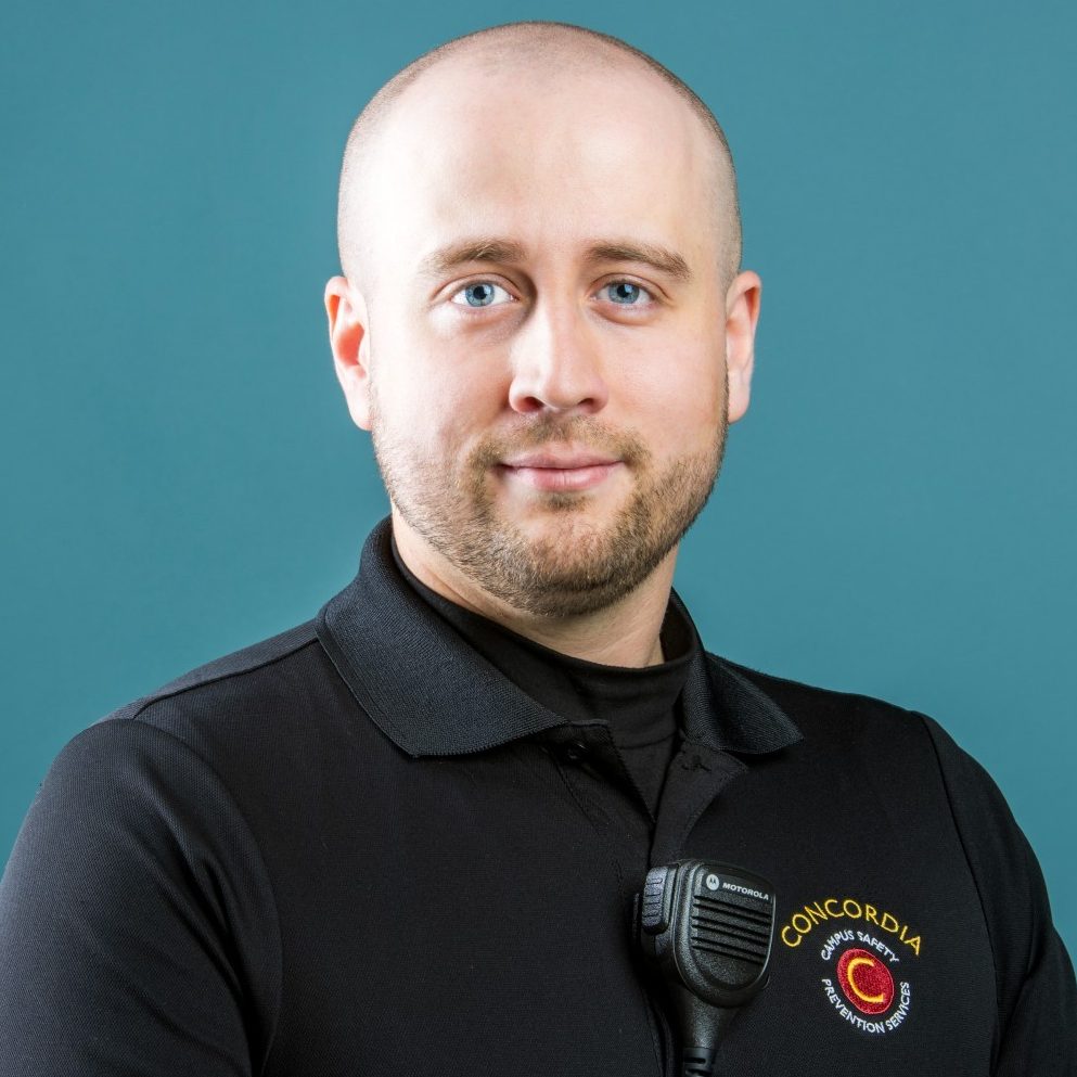 A person in a black polo with a Concordia logo stands against a blue background.