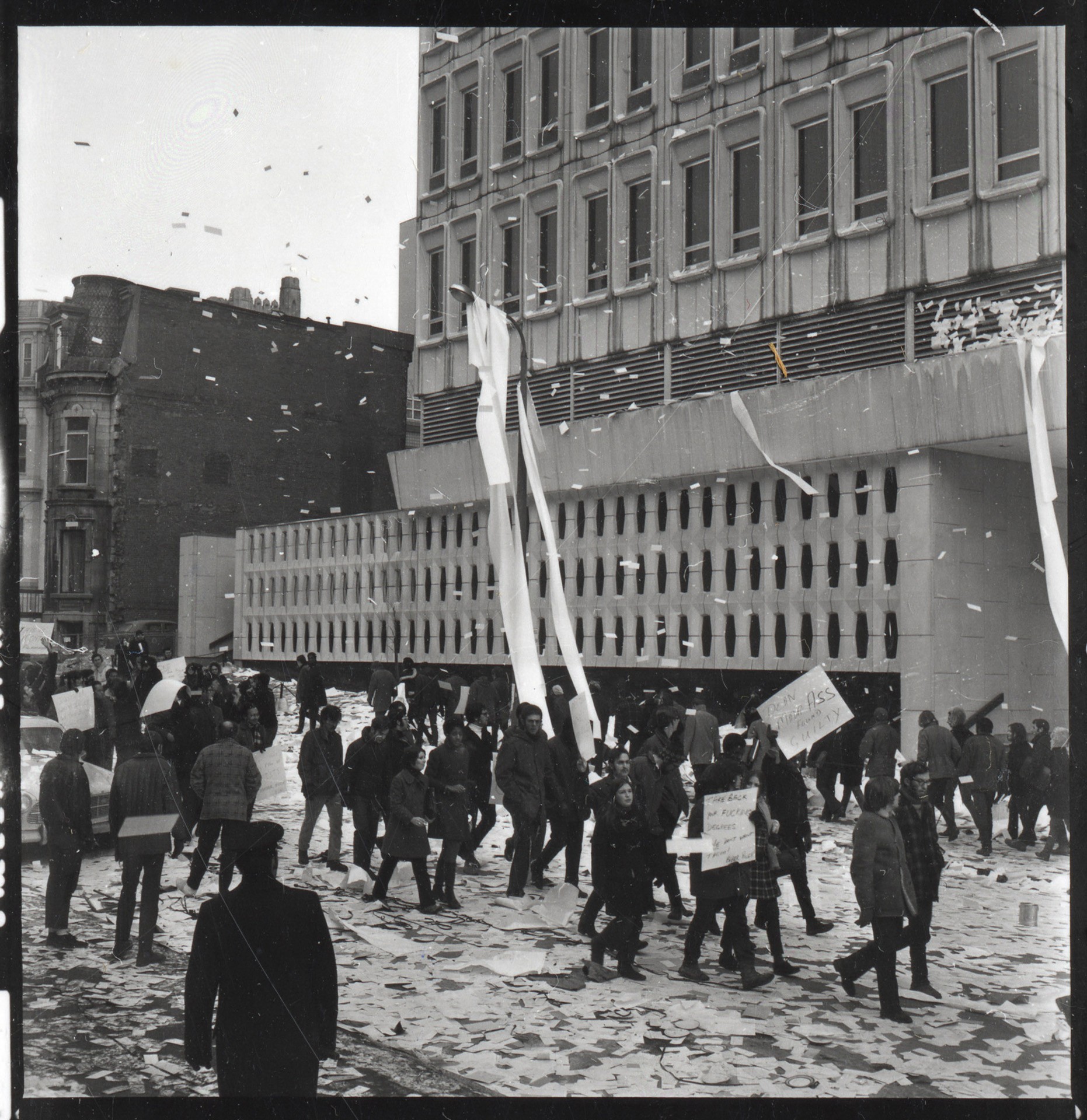 Protesters walk down Mackay Street, which is littered with computer paper and data cards.