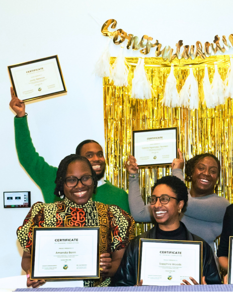 Photograph of a group holding up certificates in front of a "Congratulations" sign