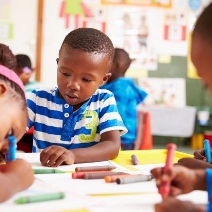 Photo of Black kids seated and drawing in a classroom