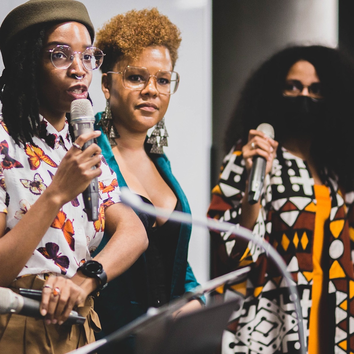 Photo of three Black women holding microphones giving a presentation
