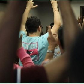 A photograph taken in the middle of a crowd of people holding up their hands during an activity.
