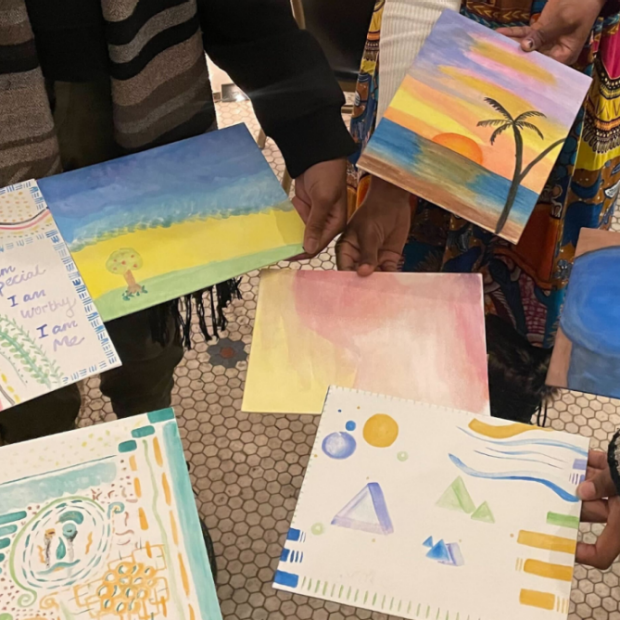 A photograph of hands holding various watercolour paintings.