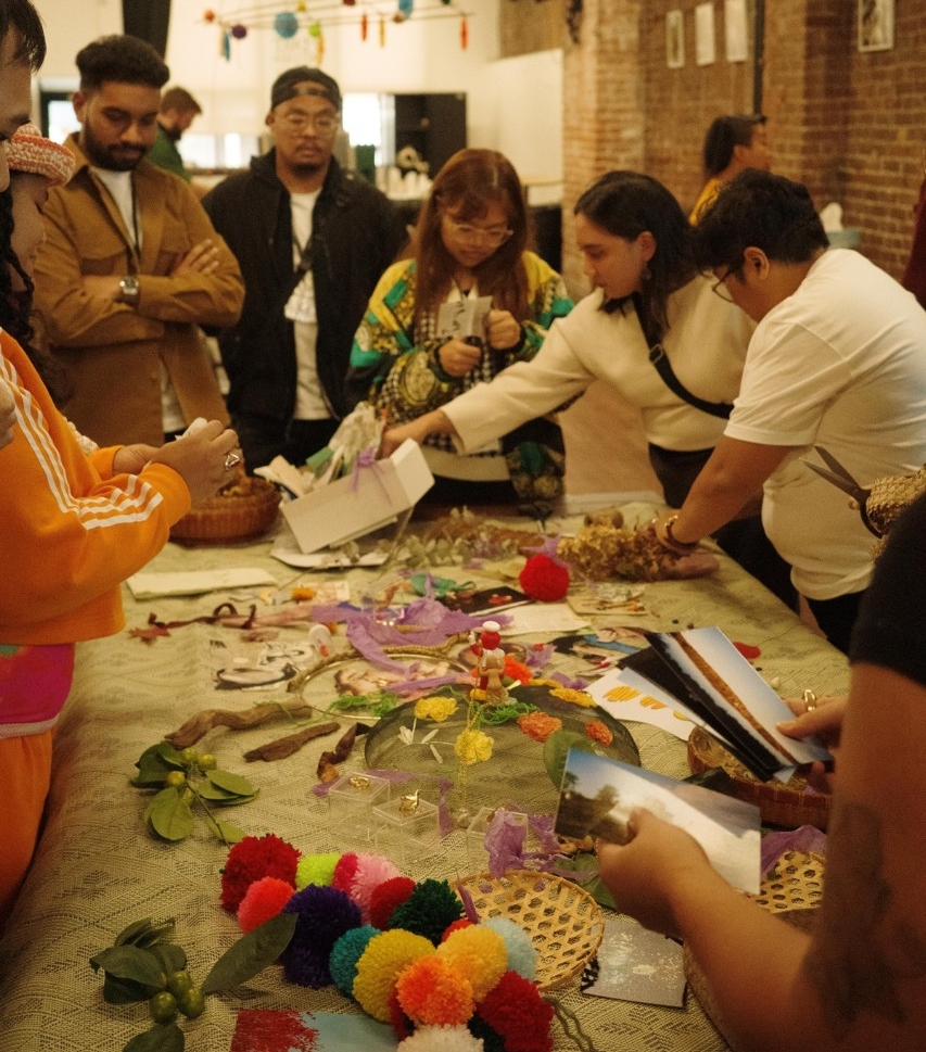 People gathered around a table, looking at art materials
