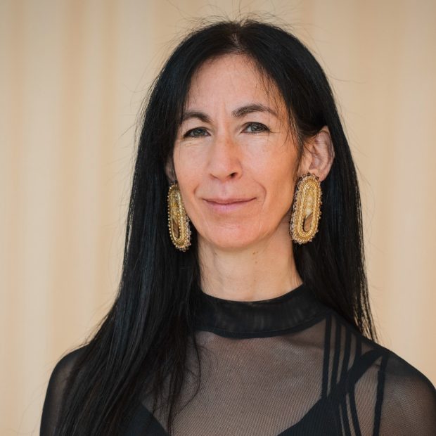 Portrait of smiling woman with long, dark hair and funky, bold, gold earrings