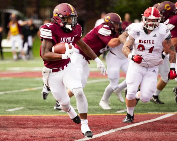 A Stingers football player, wearing a throwback Loyola College jersey, runs with the ball