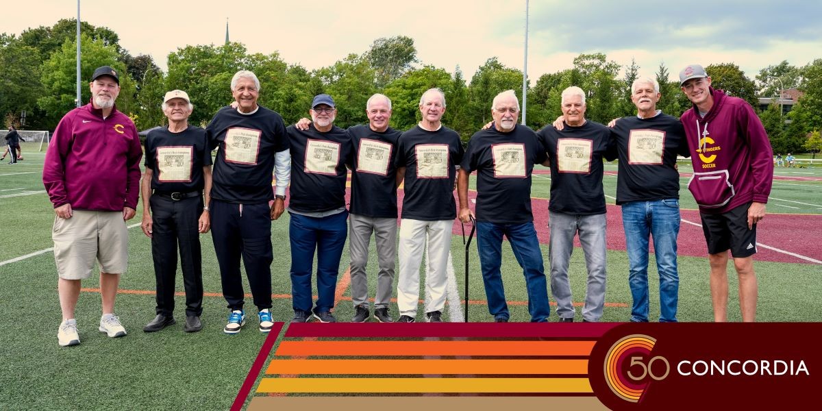 Alumni soccer players stond on the pitch and smile.