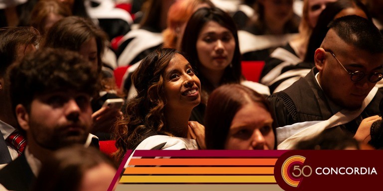 A young woman sits among her classmates wearing their ceremonial gowns at convocation.