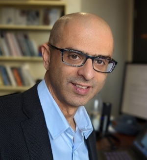 Image of Professor Eldad Tsabary with computer and bookshelf in the background