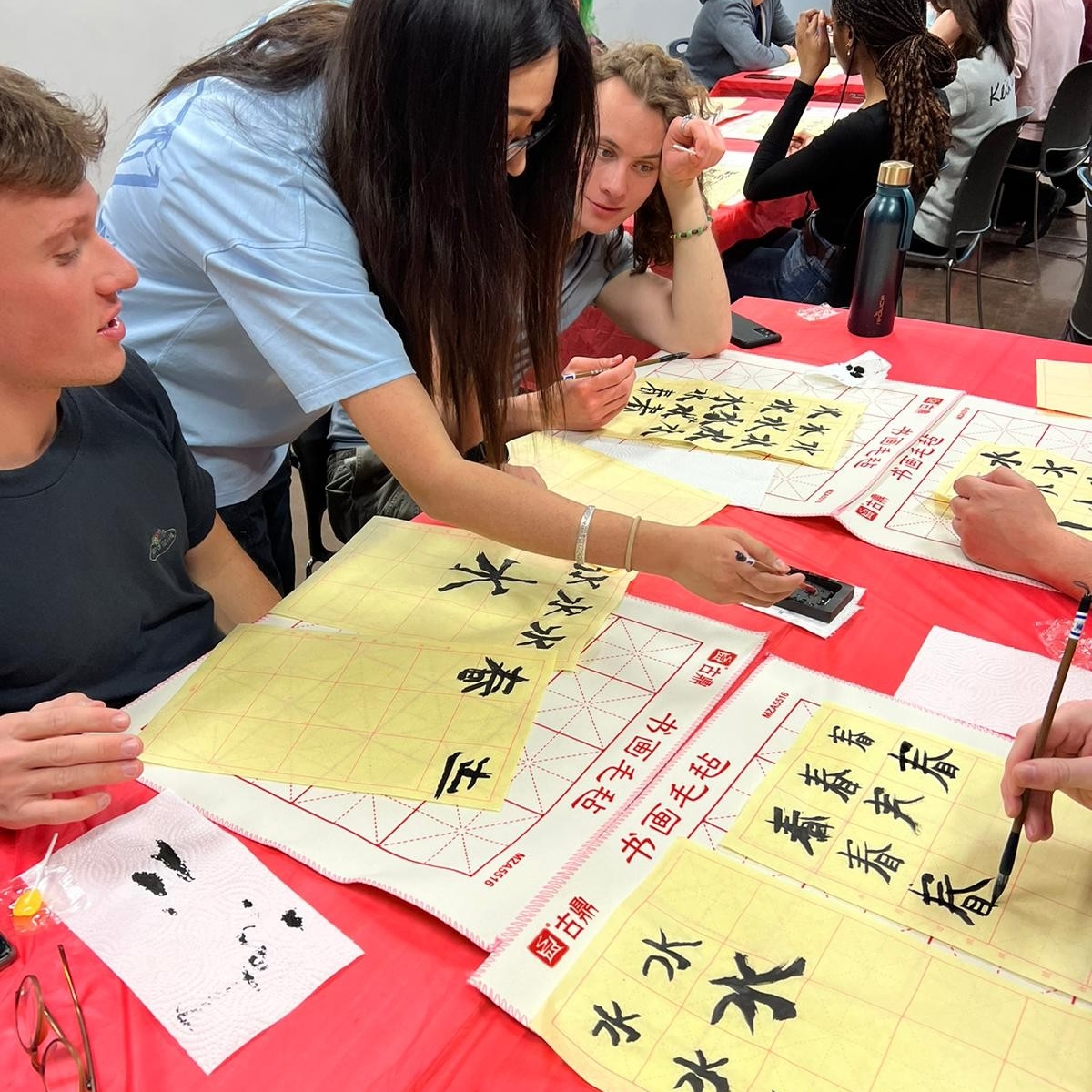 A tutor works with members of MOCHI practicing writing Chinese characters.