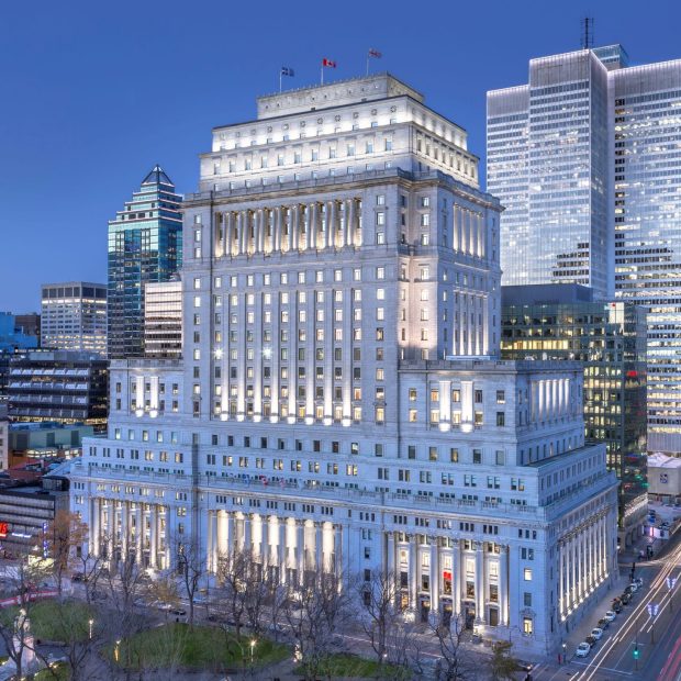 Aerial photograph capturing the Sun Life Building in Montreal at dusk. The building stands out with its grand, historical architecture amidst the modern cityscape, showcasing a blend of classic and contemporary structures.