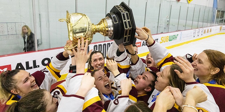 Members of the Stingers women's hockey team hoist the winning cup over their heads